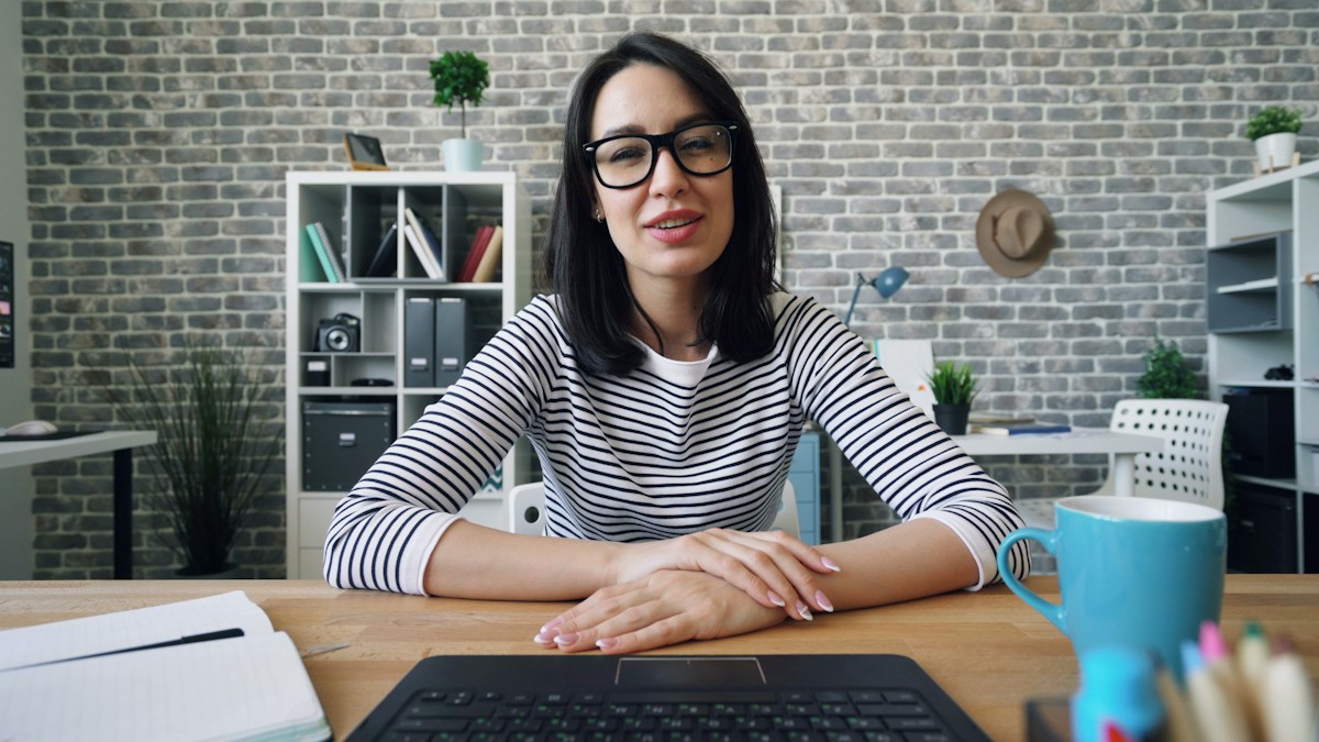 Operations manager in a striped top seated at her desk during an office video call